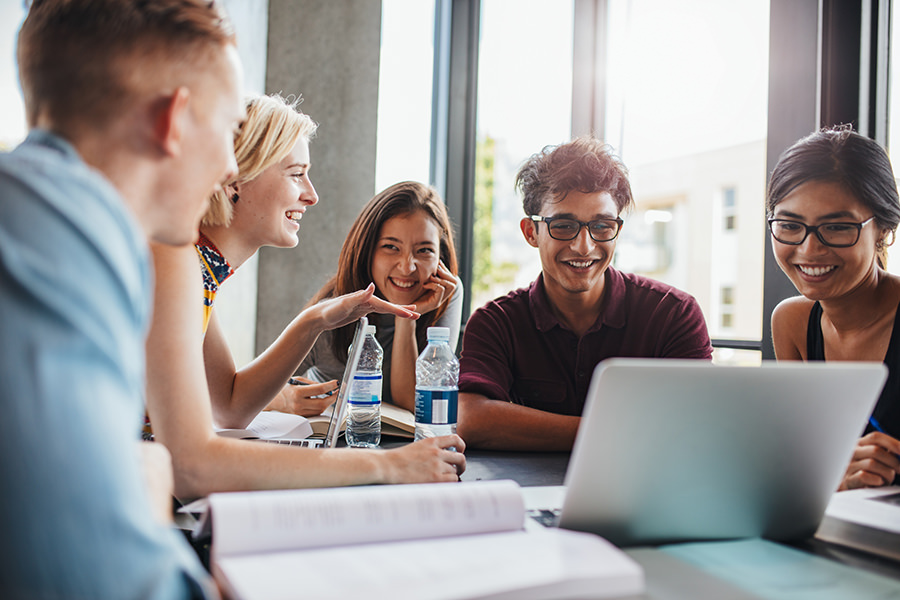 Students interacting with computer at a table.